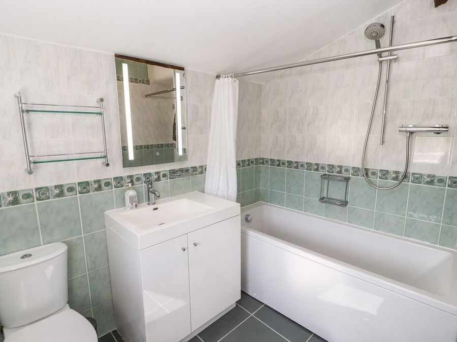 A bathroom with a bathtub shower combination a sink with cabinet mirror and toilet at Roger Pot in Garsdale near Sedbergh
