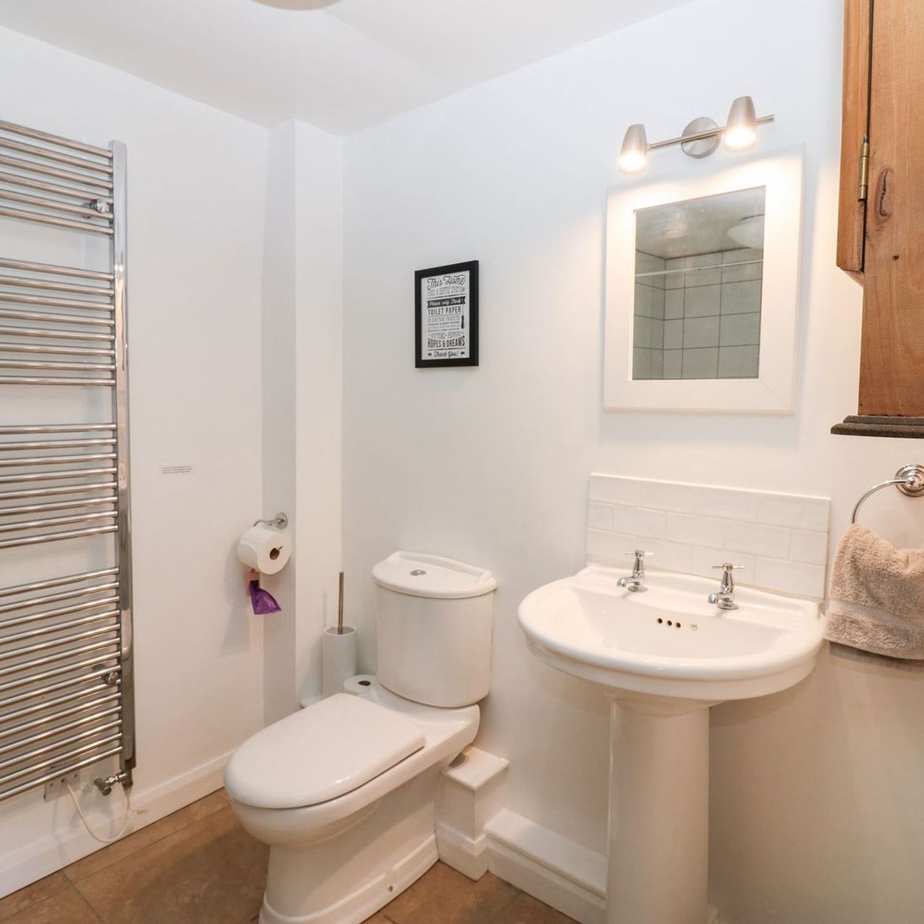 A view across the ground floor shower room at Farrier's Cottage, showing the heated towel rail, WC, pedestal basin and mirror