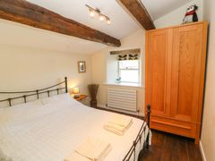 A bedroom with a bed a wooden wardrobe a window and exposed wooden beams at Roger Pot in Garsdale near Sedbergh