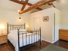 A bedroom with a metal bed frame wooden bedside tables lamps and exposed wooden ceiling beams at Roger Pot in Garsdale near Sedbergh