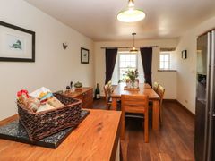 A dining room with a wooden table and chairs a wicker basket with food on a counter and framed pictures on the walls at Roger Pot in Garsdale near Sedbergh
