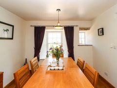 A dining room with a wooden table and chairs flowers in a vase and tea set on the table at Roger Pot in Garsdale near Sedbergh