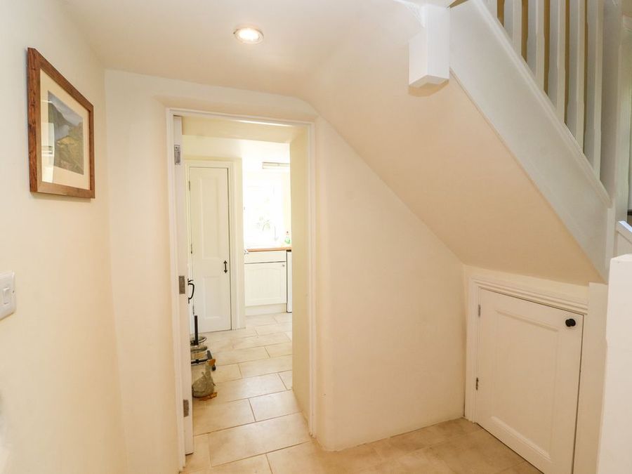 A hallway with tiled floor and a storage door under the stairs leading to a kitchen at Roger Pot in Garsdale near Sedbergh