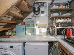 A kitchen corner with a countertop holding a small blue cabinet glassware bread box microwave red kettle and hanging pans and cups at The Old Cart House in Garsdale near Sedbergh