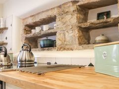 A kitchen countertop with kettles cups and a green pot in stone shelves at Roger Pot in Garsdale near Sedbergh