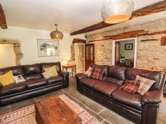 A living room with two brown leather sofas a wooden coffee table and exposed stone walls at Roger Pot in Garsdale near Sedbergh
