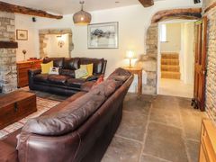 A living room with two leather sofas a wooden chest and side table with lamp at Roger Pot in Garsdale near Sedbergh
