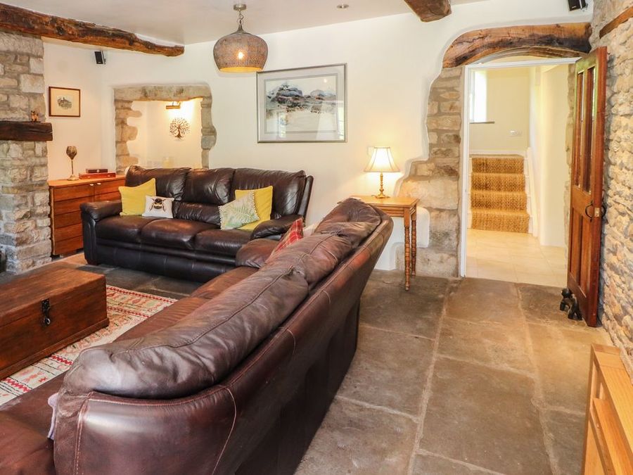 A living room with two leather sofas a wooden chest and side table with lamp at Roger Pot in Garsdale near Sedbergh