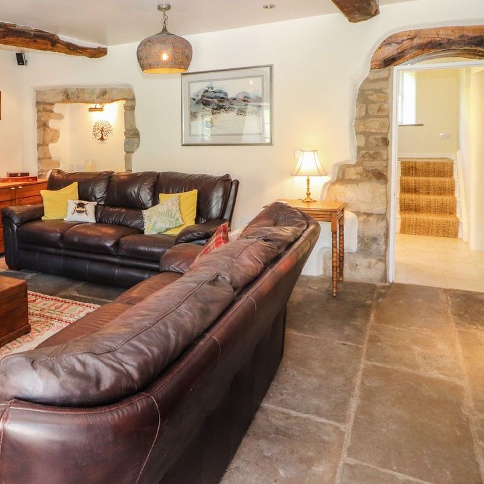 A living room with two leather sofas a wooden chest and side table with lamp at Roger Pot in Garsdale near Sedbergh