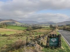 A road with a Yorkshire Dales National Park sign and fields and hills in the background at The Old Cart House in Garsdale near Sedbergh