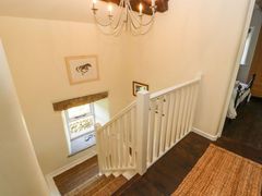 A staircase with white railing and wall art near a window at Roger Pot in Garsdale near Sedbergh