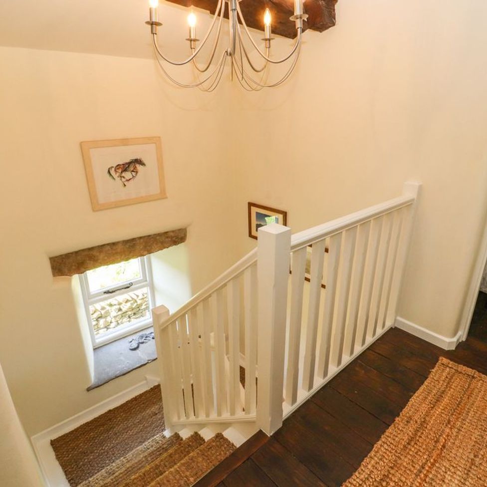 A staircase with white railing and wall art near a window at Roger Pot in Garsdale near Sedbergh