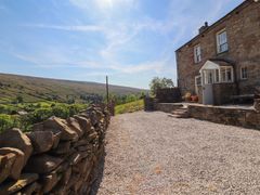 A stone cottage with gravel driveway and dry stone wall overlooking green hills at Roger Pot in Garsdale near Sedbergh