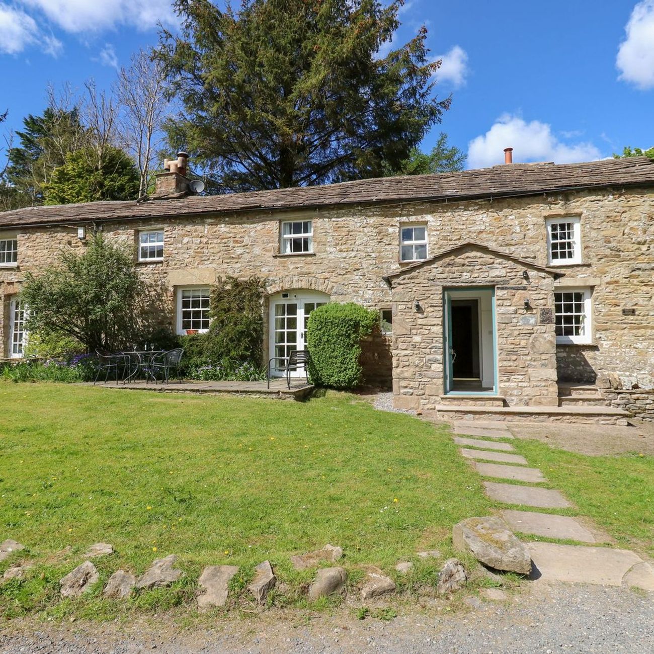 Farrier's Cottage seen from the driveway, with a flagged path across the lawn to the porch