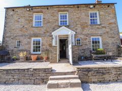 A stone house with white framed windows a bench and potted plants at Roger Pot in Garsdale near Sedbergh