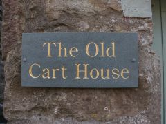 A stone wall with a rectangular plaque that says The Old Cart House