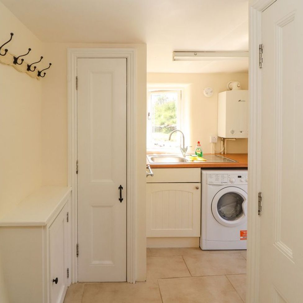 A utility room with a washing machine a sink and hooks on the wall at Roger Pot in Garsdale near Sedbergh