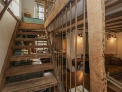 A wooden staircase with metal railings inside a room with a small dining area and a sofa at The Old Cart House in Garsdale near Sedbergh