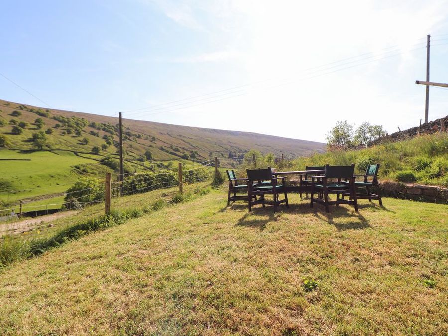 An outdoor seating area with chairs and a table on grass near a fence in a rural landscape at Roger Pot in Garsdale near Sedbergh