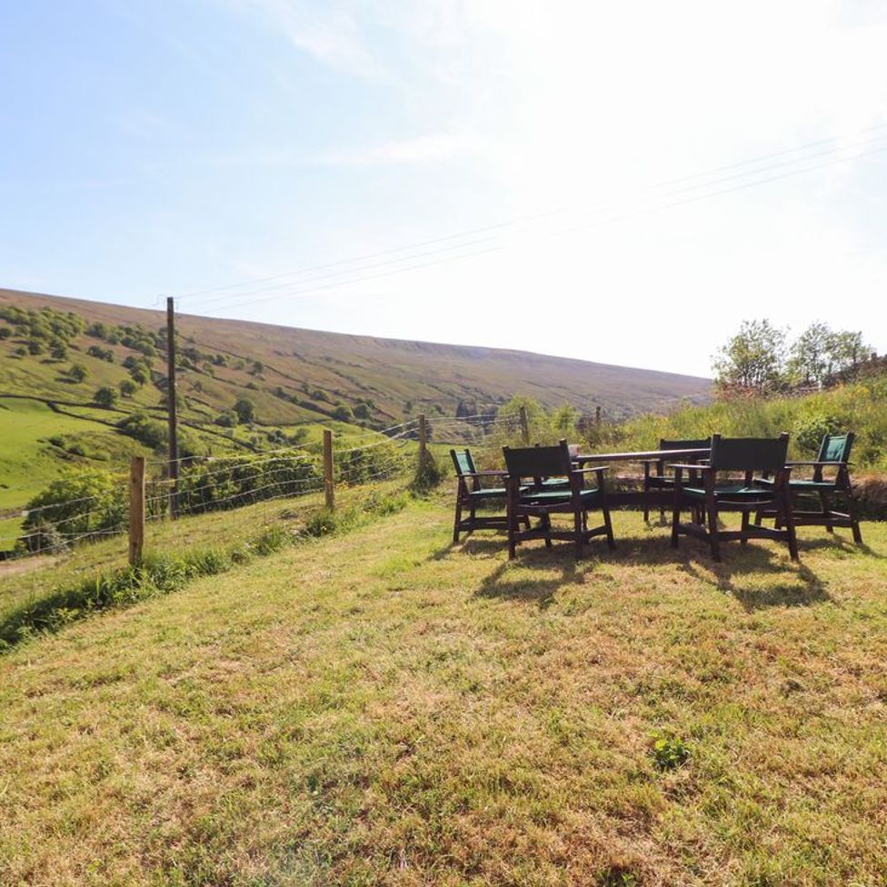 An outdoor seating area with chairs and a table on grass near a fence in a rural landscape at Roger Pot in Garsdale near Sedbergh