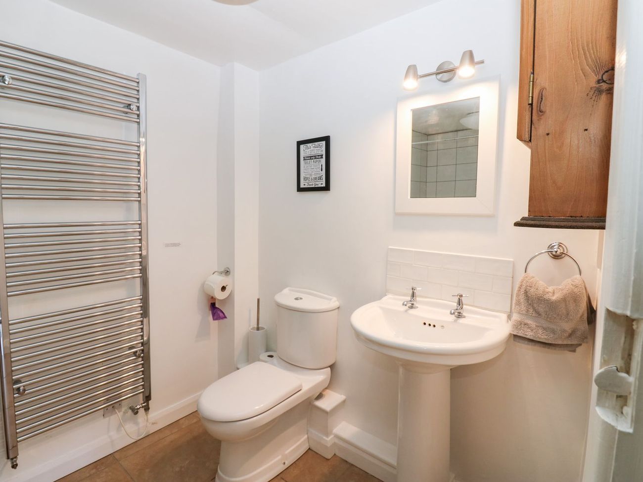 A view across the ground floor shower room at Farrier's Cottage, showing the heated towel rail, WC, pedestal basin and mirror