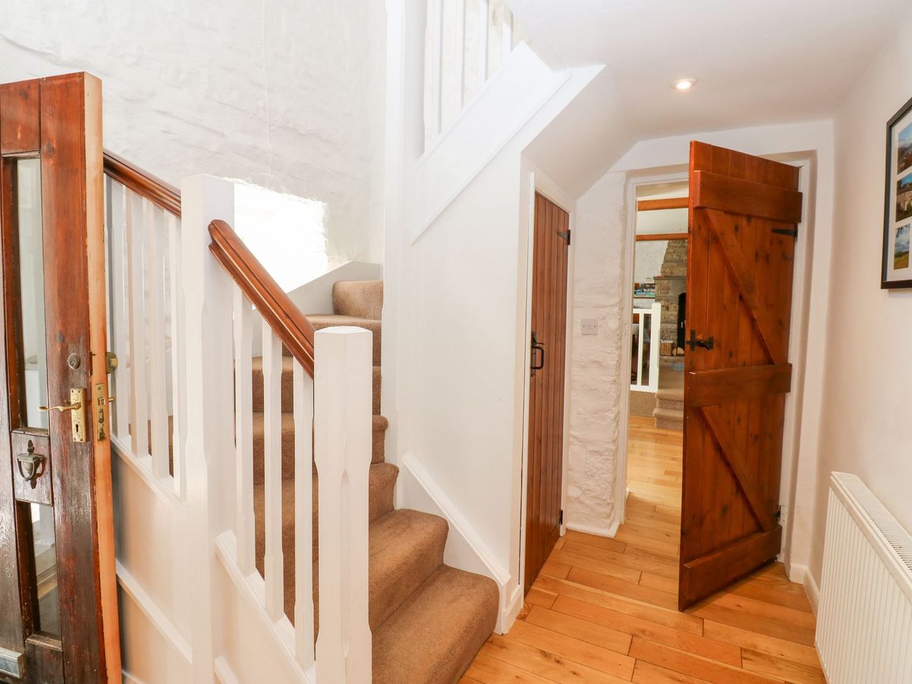 The foot of the stairs at Farrier's Cottage, with pine plank doors opening onto the sitting room