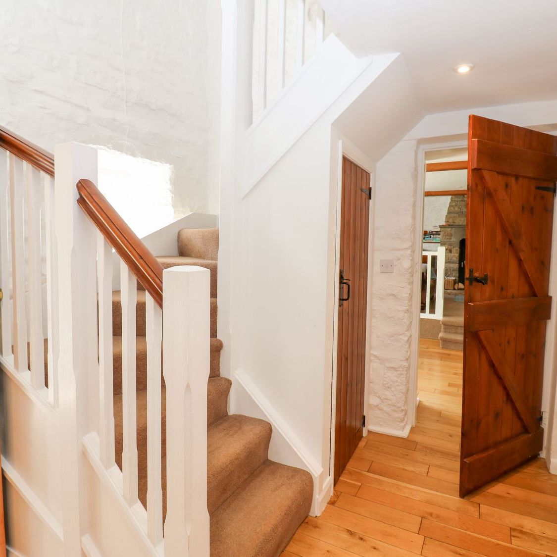 The foot of the stairs at Farrier's Cottage, with pine plank doors opening onto the sitting room