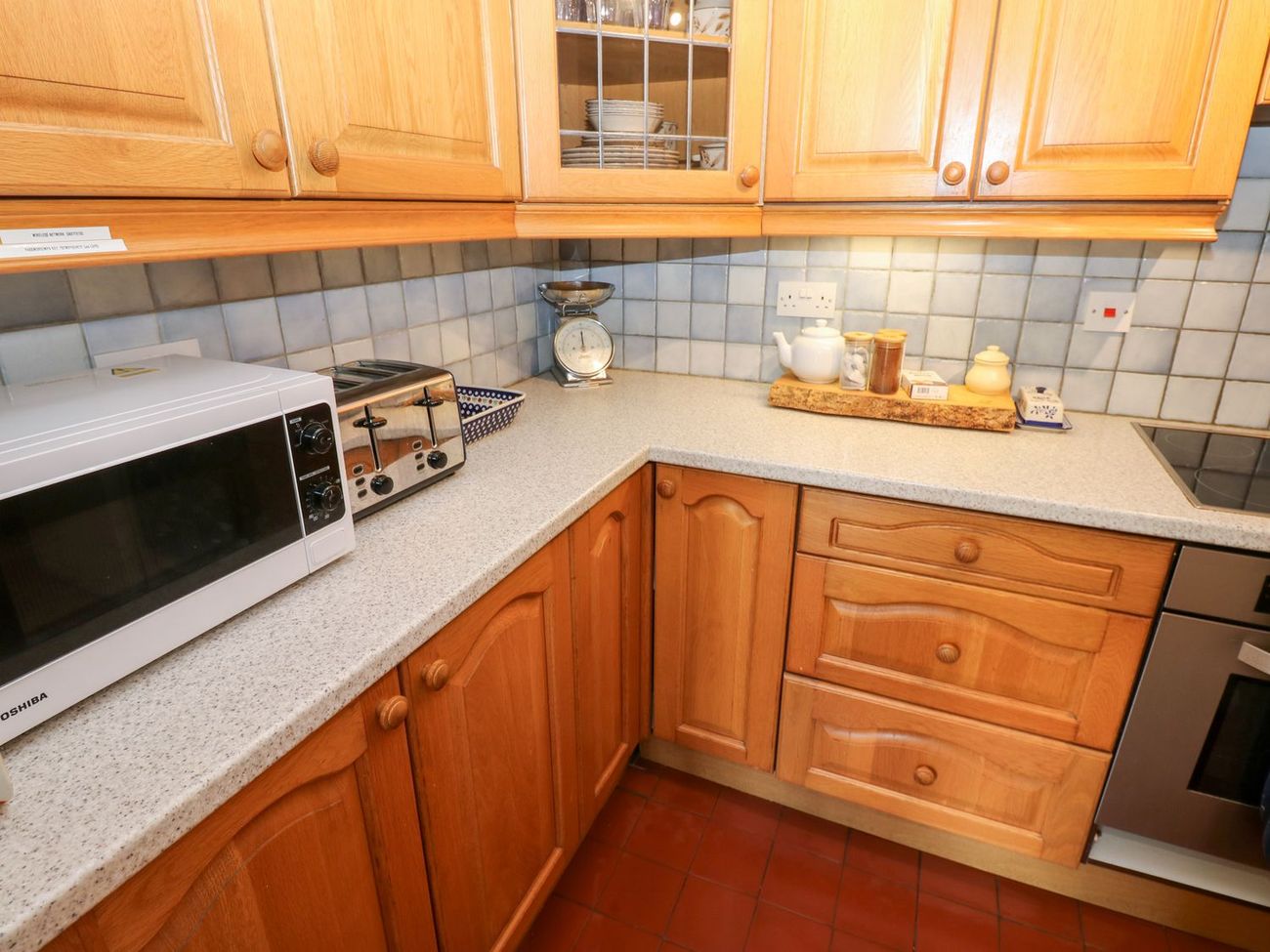 The kitchen worktop at Farrier's Cottage, with a microwave, toaster, kitchen scales and a tray of tea things