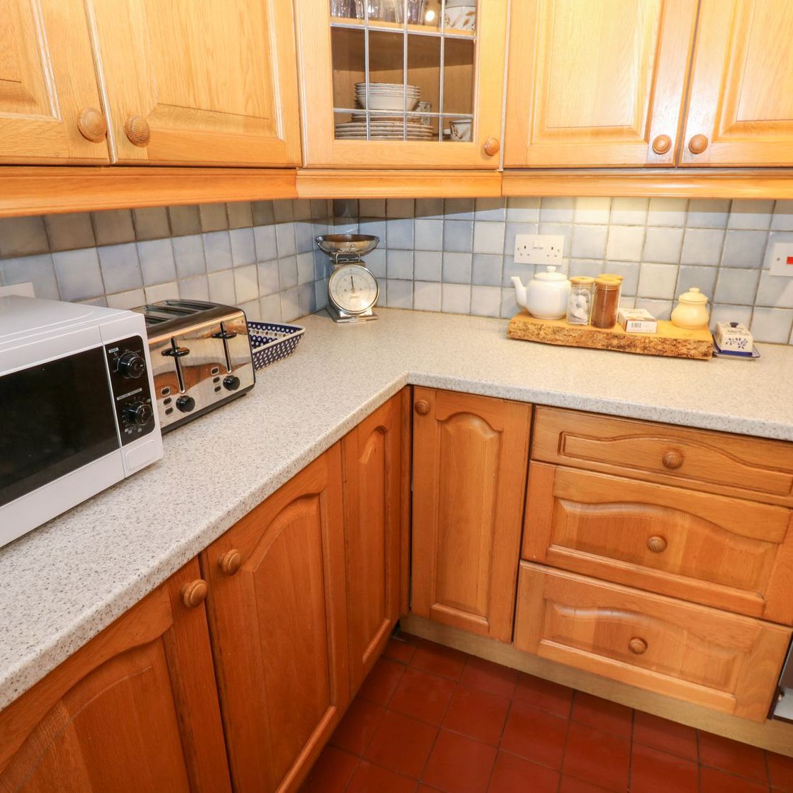 The kitchen worktop at Farrier's Cottage, with a microwave, toaster, kitchen scales and a tray of tea things