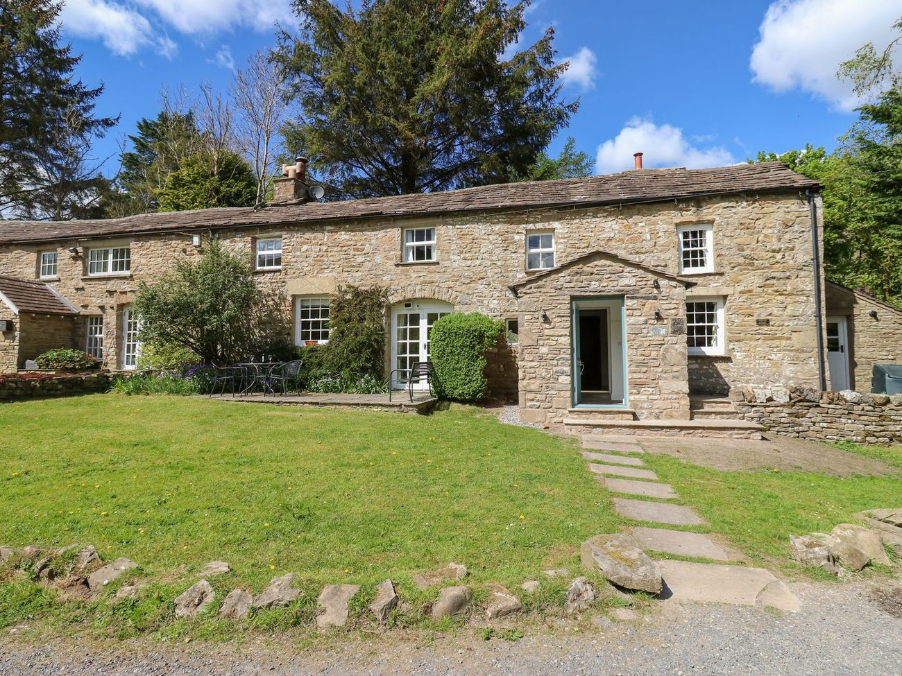 Farrier's Cottage seen from the driveway, with a flagged path across the lawn to the porch