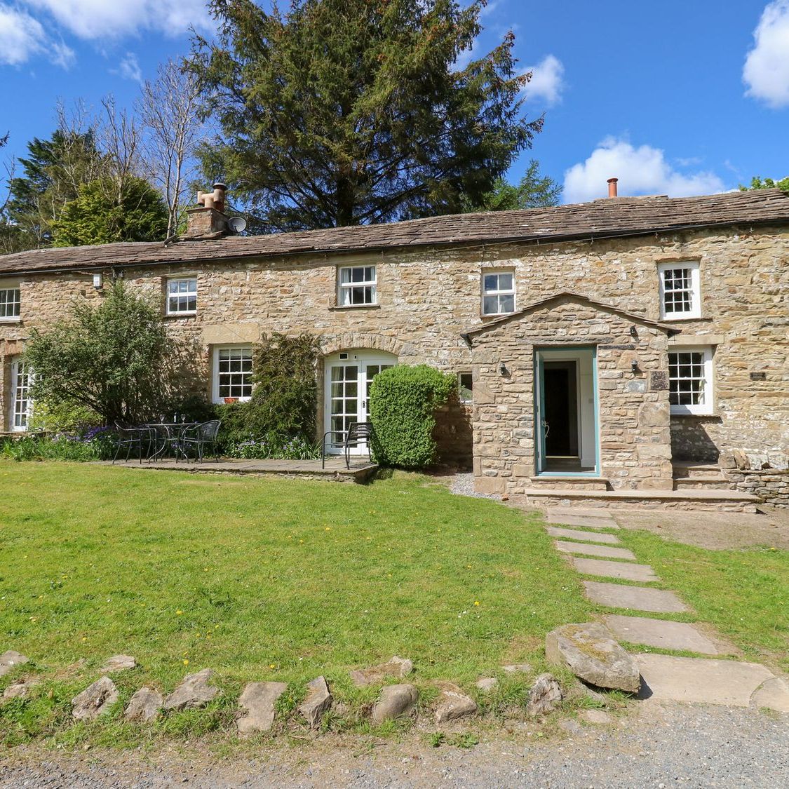 Farrier's Cottage seen from the driveway, with a flagged path across the lawn to the porch