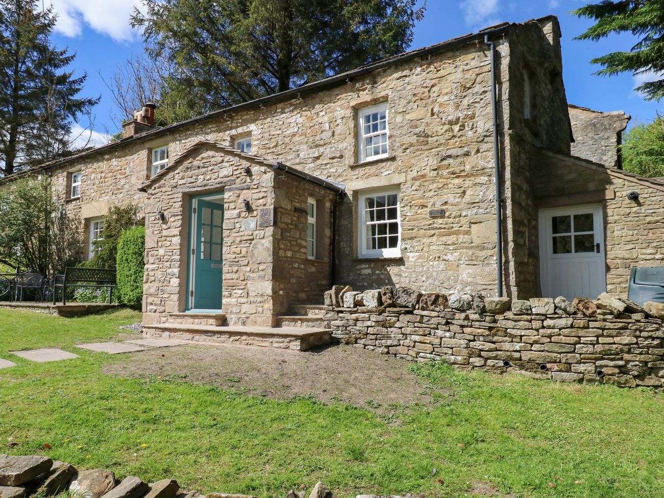 The blue front door and stone porch at Farrier's Cottage, with steps up from the lawn