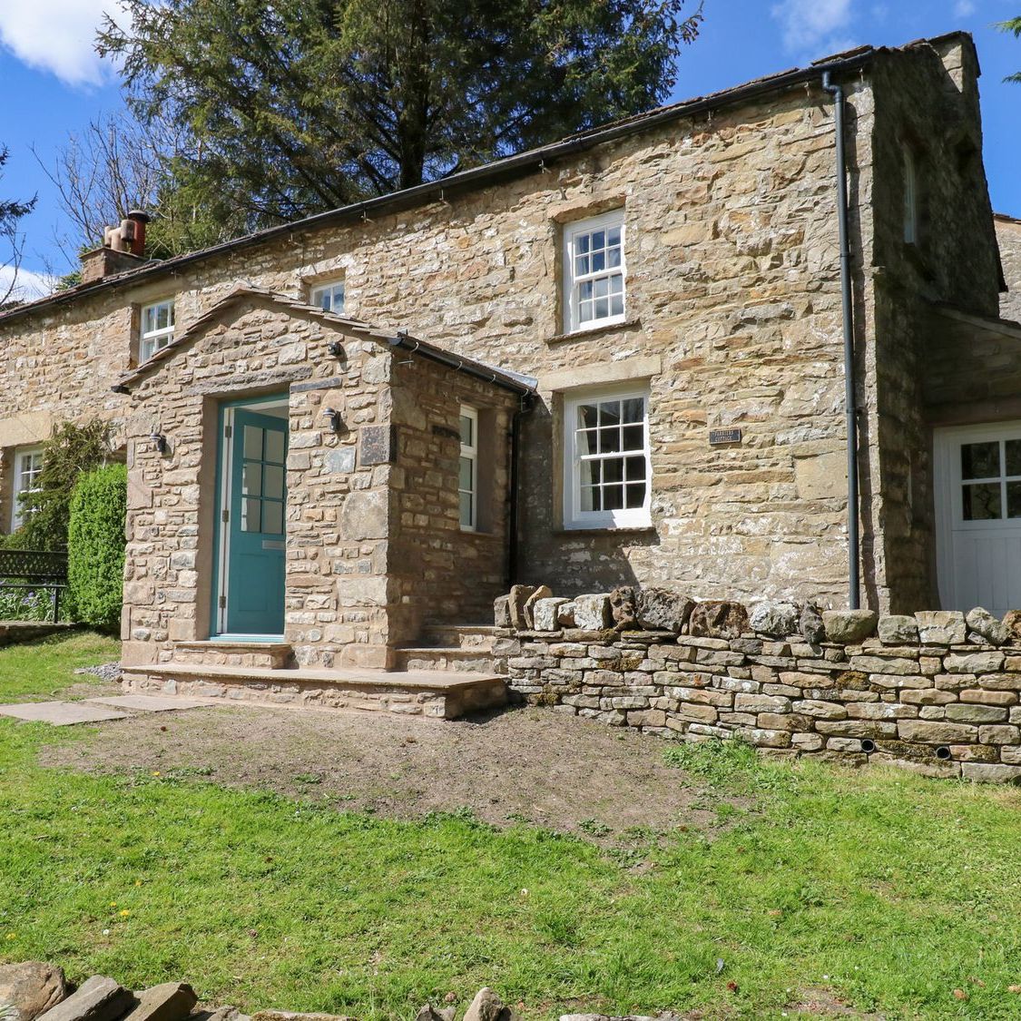 The blue front door and stone porch at Farrier's Cottage, with steps up from the lawn