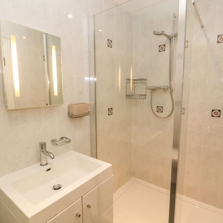 A modern cream-tiled shower room at Roger Pot with a vanity basin, mirror cabinet and walk-in glass shower