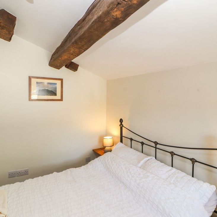 A cosy attic bedroom at Roger Pot with a metal-framed double bed, white bedding and exposed beams