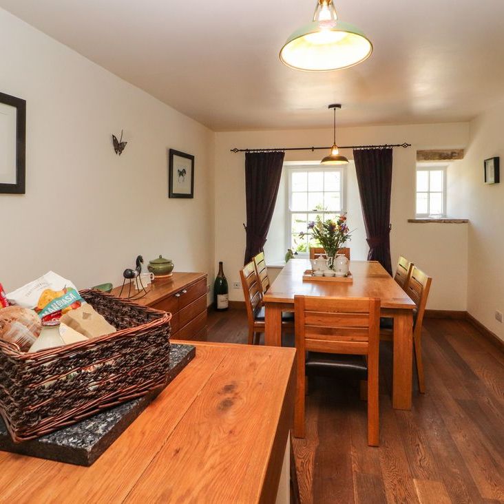 The dining area at Roger Pot with an oak table and chairs, a welcome hamper and American fridge-freezer