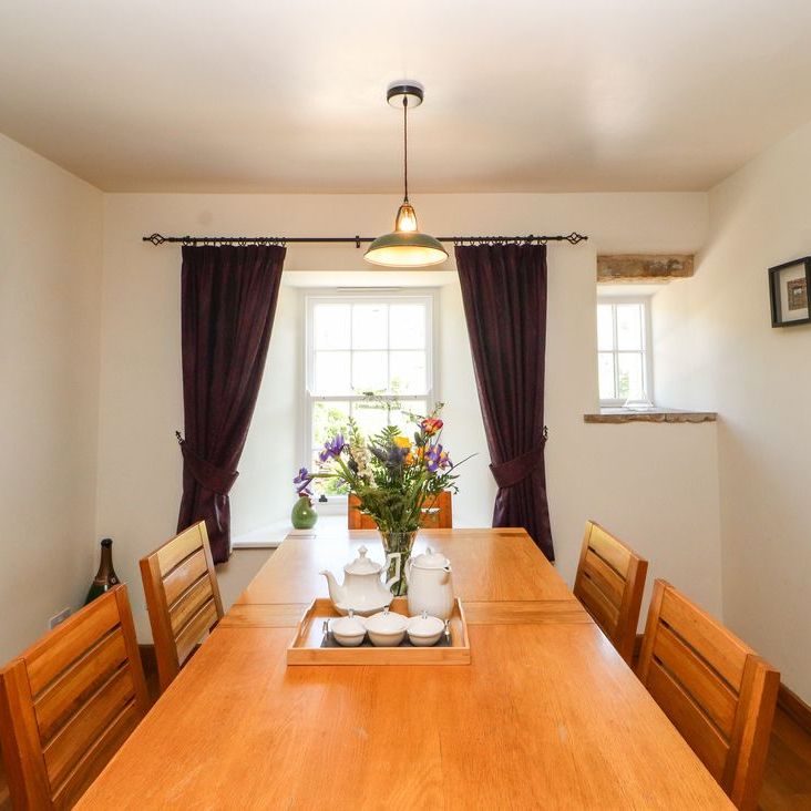 The Roger Pot dining room with a long oak table and chairs, fresh flowers and a window to the garden
