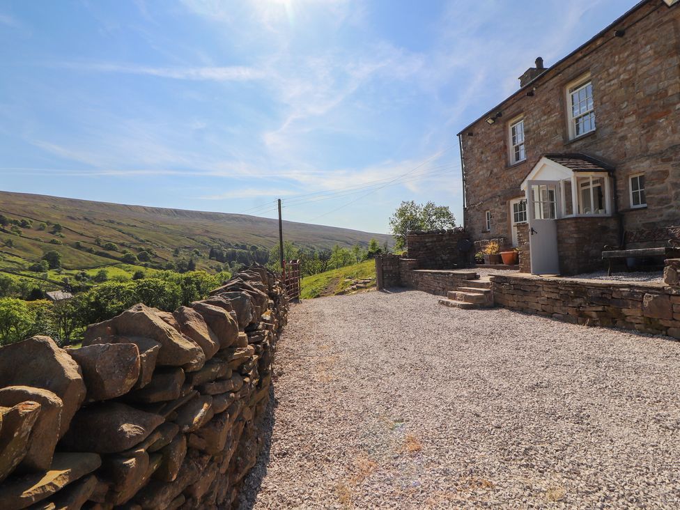 A stone cottage with gravel driveway and dry stone wall overlooking green hills at Roger Pot in Garsdale near Sedbergh