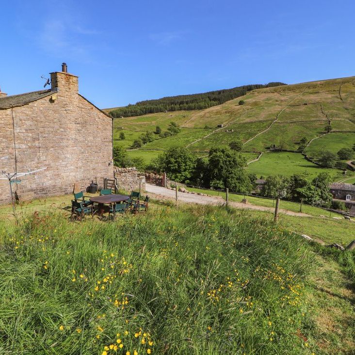 Roger Pot cottage with a garden table and chairs on the grass, looking out over the Dales valley