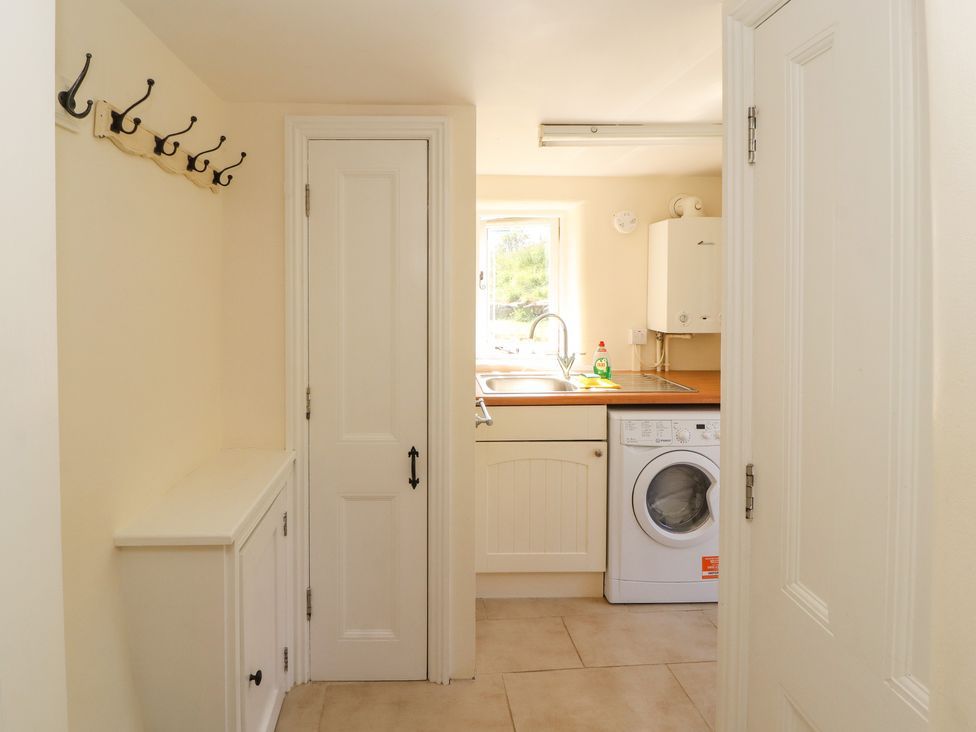 A utility room with a washing machine a sink and hooks on the wall at Roger Pot in Garsdale near Sedbergh