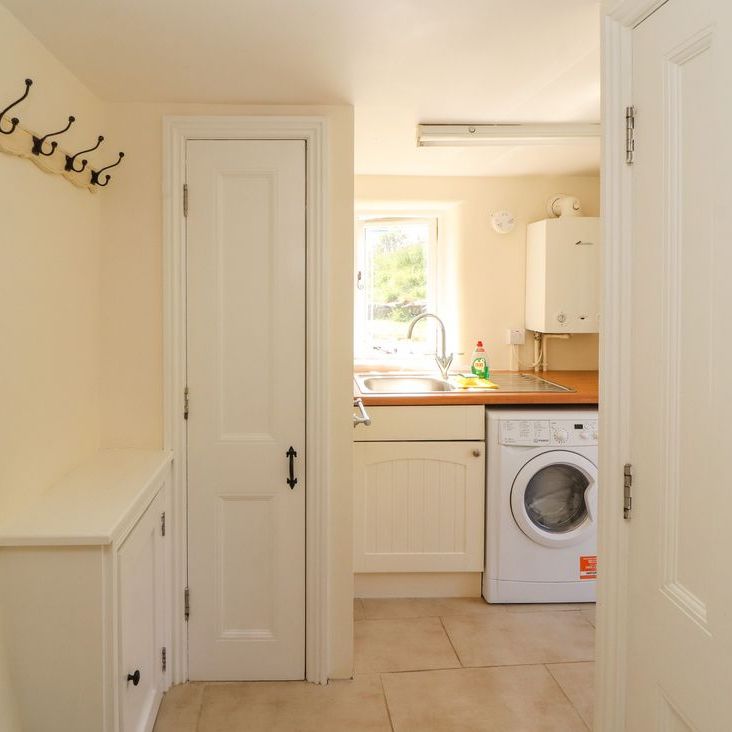 The utility room at Roger Pot with a washing machine, sink, peg rail and coat hooks