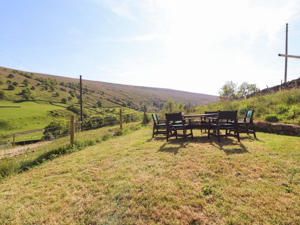 An outdoor seating area with chairs and a table on grass near a fence in a rural landscape at Roger Pot in Garsdale near Sedbergh