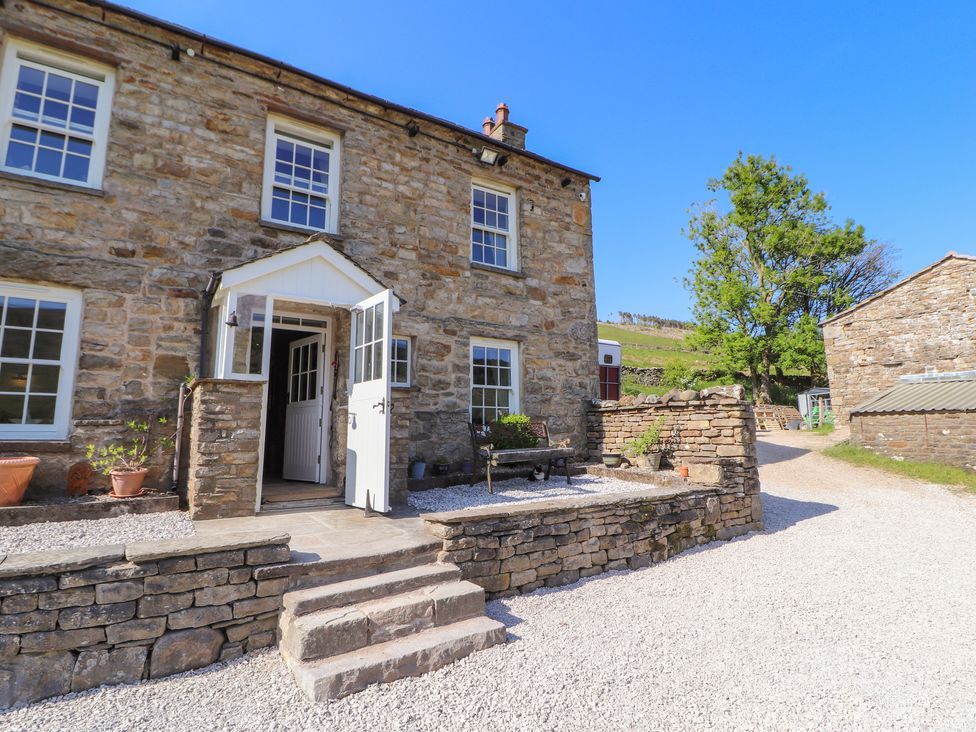 Stone house with white doors and windows gravel pathway stone steps and bench at Roger Pot in Garsdale near Sedbergh