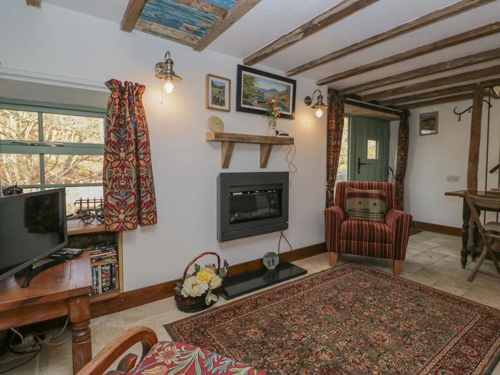A living room with a fireplace armchair patterned curtains and a television at The Old Cart House in Garsdale near Sedbergh