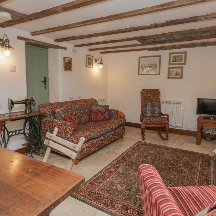 A traditional living room at The Old Cart House with floral sofas, a vintage Singer sewing machine and beams