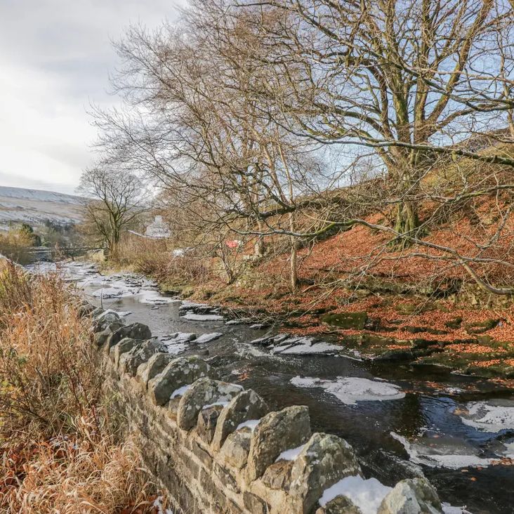 A winter lane beside a dry-stone wall and a partly frozen beck near The Old Cart House