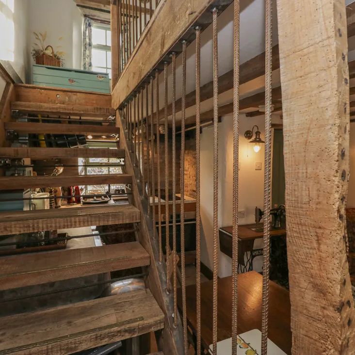 The open-tread wooden staircase at The Old Cart House, with a Singer sewing machine and patterned sofa beyond